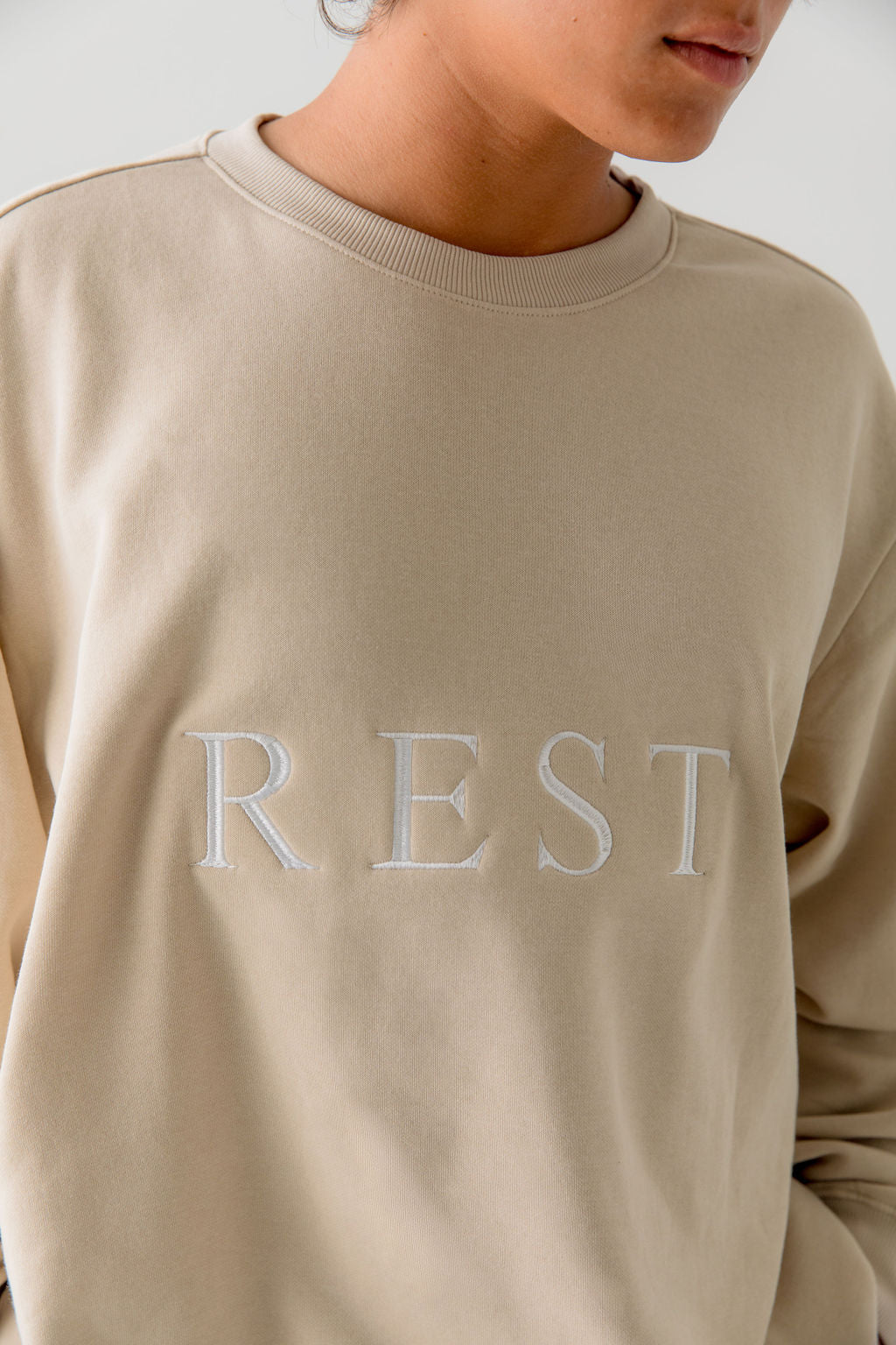 Unisex beige pullover cotton sweatshirt with " rest" embroidered in white