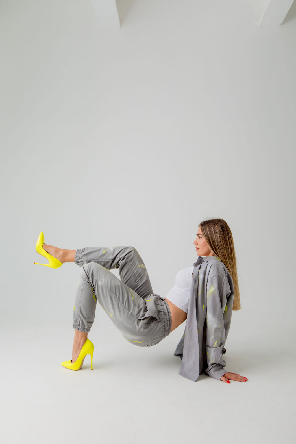 woman wearing gray button down and joggers with yellow and white paint splatters and yellow high heels